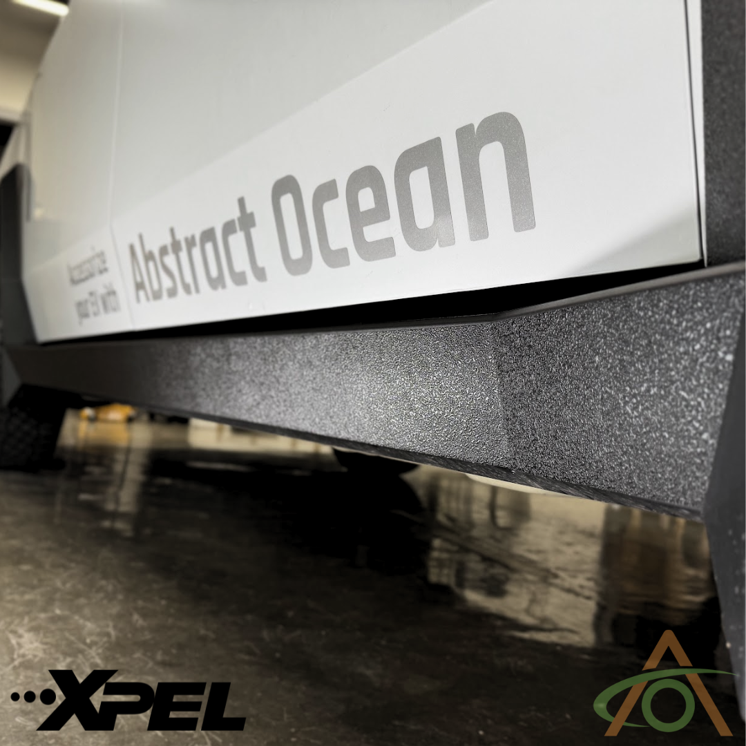 A vehicles close-up reveals Abstract Ocean on its textured surface, featuring XPEL logos reminiscent of expertly shielded rocket panels with Ultra-Tough Xpel Armor Rocker Protection for Cybertruck.