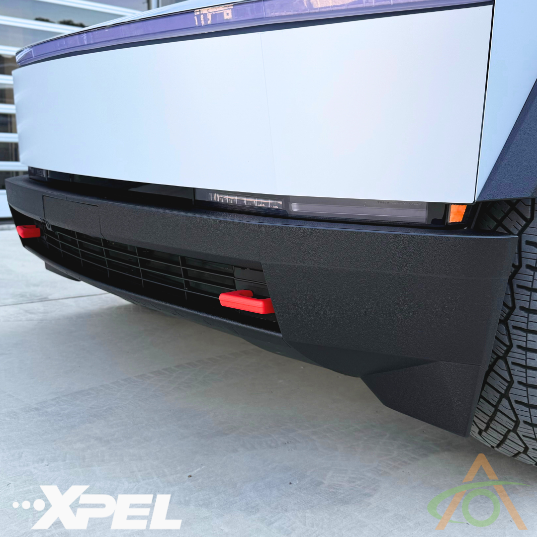 The front bumpers minimalist design is enhanced by Abstract Oceans Ultra-Tough Xpel Armor for Cybertruck, featuring a red tow hook. The XPEL logo appears on the lower left, while a geometric logo on the right exudes sleek protection film elegance.