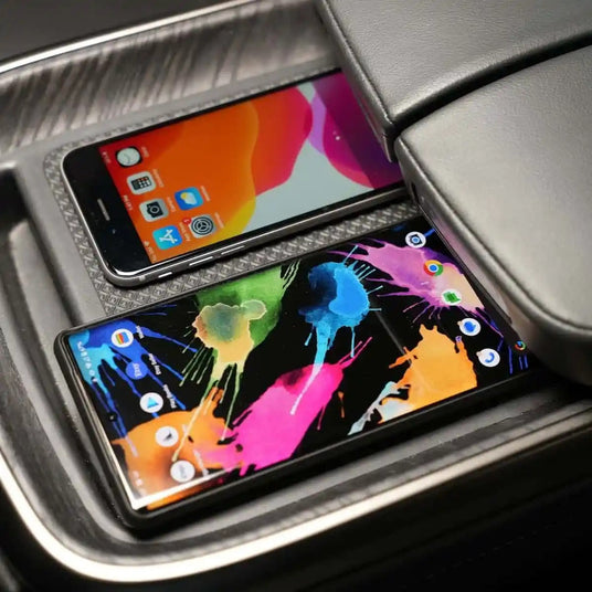 Two smartphones with colorful screens placed side by side in a cars center console.