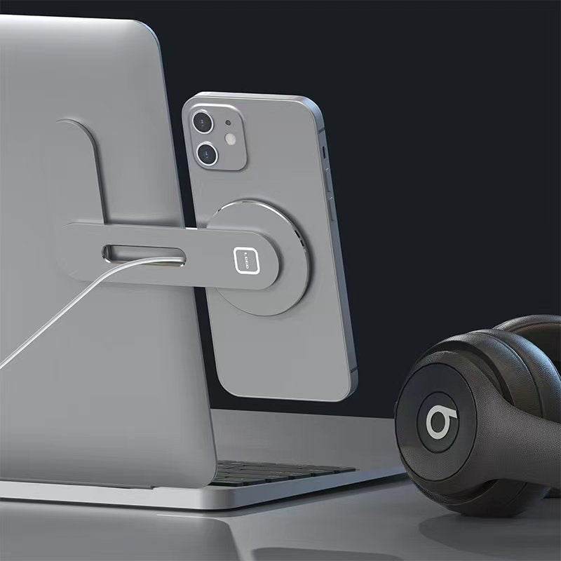 A smartphone is magnetically attached to a laptop using the Tesery Official Store Wireless Magsafe Mount for Tesla Model 3/Y/S/X/Cybertruck, while a pair of Beats headphones rests on the desk nearby.