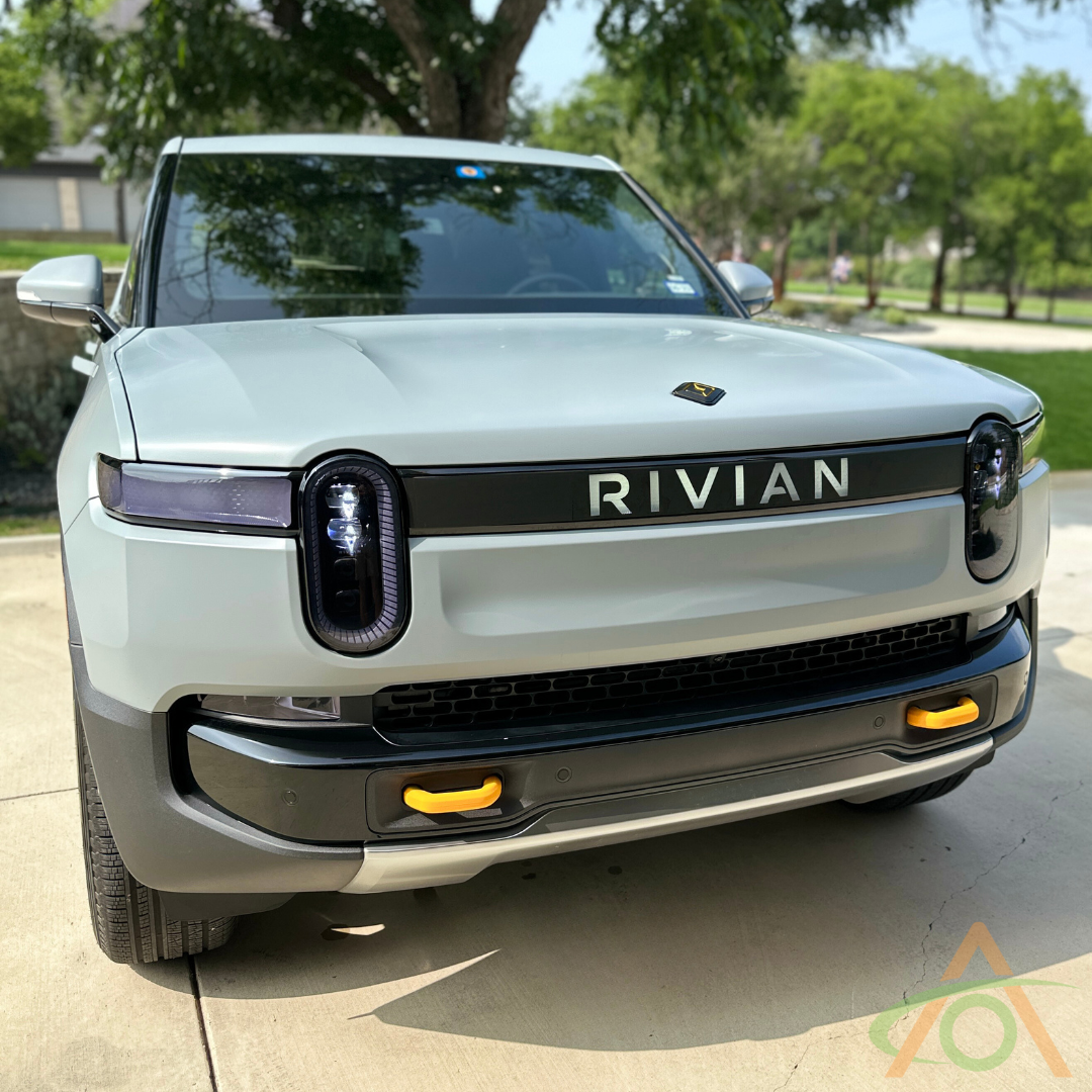 Front view of a Rivian electric truck in a sunny setting, highlighting its latest hook upgrade with sleek Silicone Hook Covers from Abstract Oceans new accessories line.