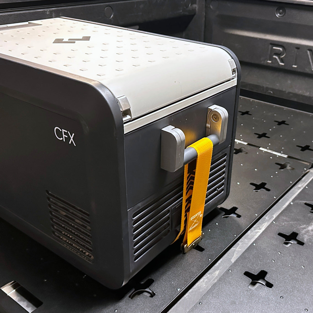 A Thunderbolt Adventure Supply R1T Bed Glider, secured with a yellow strap, sits in the cargo area—making it an ideal camping accessory for efficient truck bed storage.