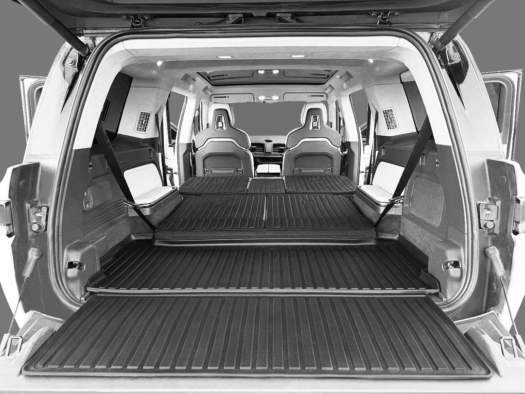 Interior view of a 2022-2026 Rivian R1S with seats folded flat, showcasing spacious cargo, a durable thermoplastic floor mat, and LinerX Seat Back Cover Mats for extra rear seat protection.