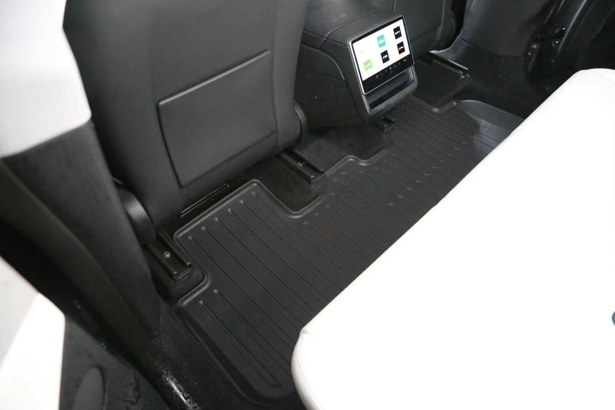 Backseat view of a 2026 Tesla Model Y (Juniper) interior with LinerX Floor Mats in black, showing the backs of two front seats and a center console with USB ports and air vents.