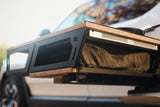 Close-up of Thunderbolt Adventure Supply’s Rivian R1T - Overland Kitchen with updated Gear Sled, featuring a storage compartment and fabric bag—ideal for organizing overland gear in your vehicle.