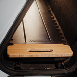 A wooden tray with a handle rests on the Thunderbolt Adventure Supply Overland Gear Sled for the Rivian R1T in a car trunk, showcasing organized gear storage.