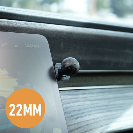 Close-up of EveryAmps 22mm Phone Mount Dash Anchor for Rivian R1T, elegantly attached to the dashboard. The device screen displays the time (10:51 AM), temperature (64°F), and part of an image, with an orange 22MM circle prominently in view. Wood grain texture adds a touch of sophistication.