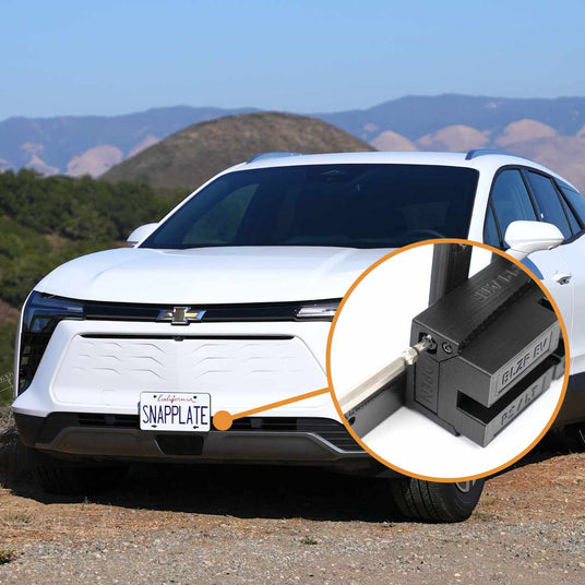 White SUV with a California license plate labeled SNAPPLATE in focus. Inset shows a close-up of the SnapPlate mounting system on the front bumper. Hills are visible in the background.