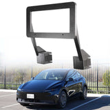 An EveryAmp Tesla Model Y SnapPlate Front License Plate Holder is displayed above a parked black car by a metal fence on a sunny day.