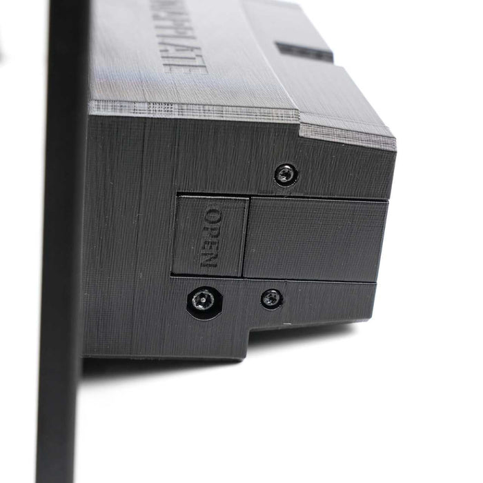 Close-up of a black plastic device with a textured surface, visible screws, and a small panel labeled OPEN next to a hexagonal socket.