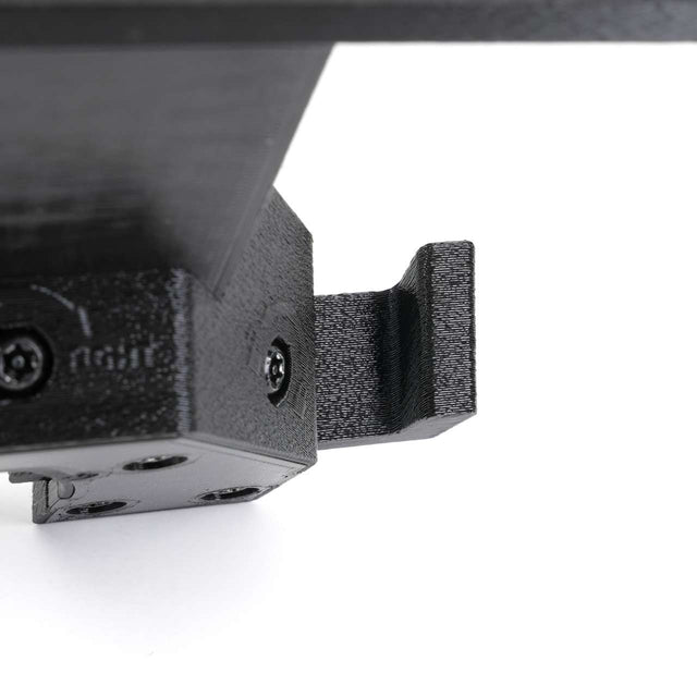Close-up view of a black 3D-printed plastic bracket secured with screws against a white background.