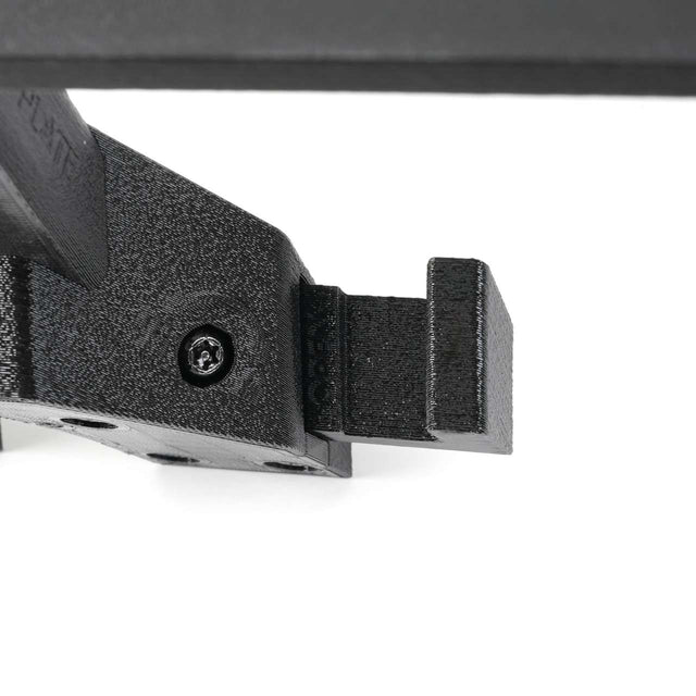 Close-up of a black, rectangular mechanical part with a screw and textured surface, attached to another component at an angle.
