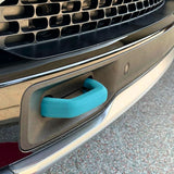Close-up of a car’s front bumper featuring a teal blue tow hook inserted into a rectangular slot below the grille, with Abstract Ocean Silicone Hook Covers - Pair offering added protection and style.