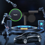 A black car is parked before robotic arms and futuristic gear, with a circular Topfit device in the background—perfect for showcasing Tesery Official Store's Magnetic Wireless Charging Phone Holder for Model 3 Highland and Model Y Juniper.