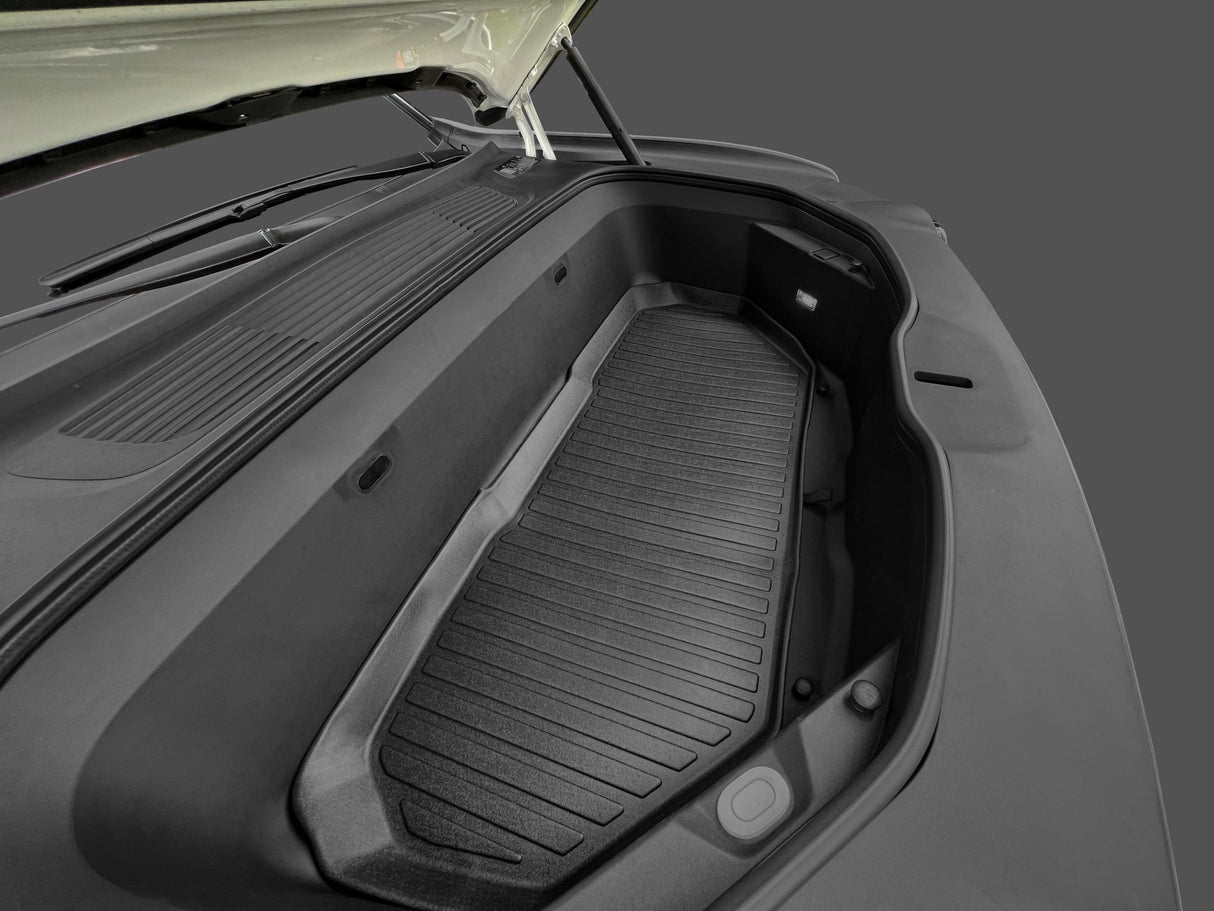 The open frunk of a car features a LinerX Front Cargo Liner for 2022-2024 Rivian R1S/R1T, offering added protection and storage under the hood, set against a plain gray background.