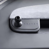 A close-up of a metallic LAUNCH button on a sleek control panel next to the Tesery Official Store Magnetic Dashboard Phone Mount for Model 3 Highland / Model Y Juniper.