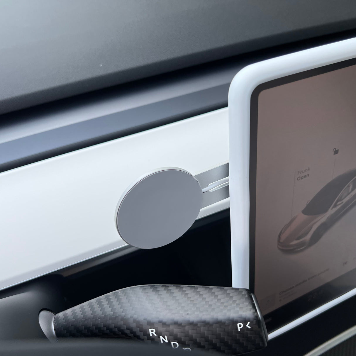 A Tesery Official Store Wireless Magsafe Mount for Tesla Model 3/Y/S/X/Cybertruck is attached to a white dashboard trim near the touchscreen display, with the gear selector (P, R, N, D) visible in the foreground.